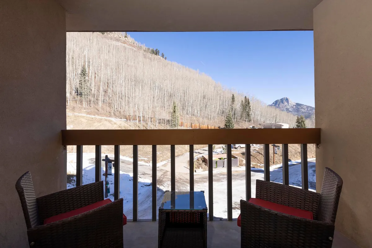 A cozy outdoor seating area looks out over a stunning mountain view, with aspen trees and soft morning light. The space feels inviting, ideal for relaxing with family or friends after a day of activities.